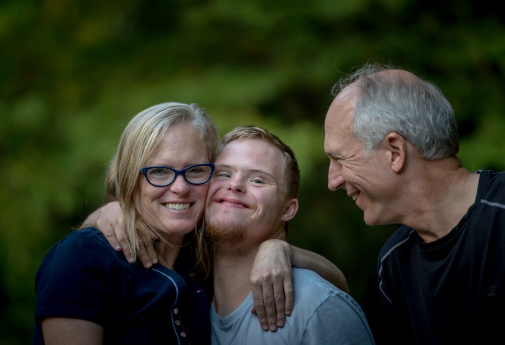 Three generations of a family embracing and laughing together outdoors.